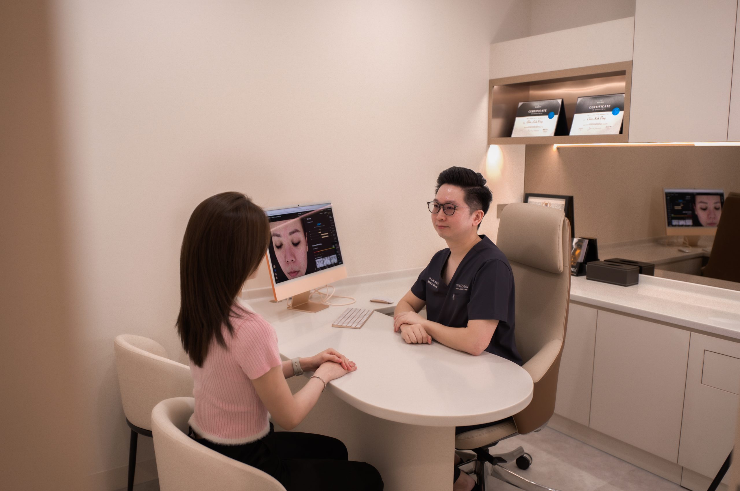 Doctor consulting a patient at a round desk with a facial skin analysis on screen