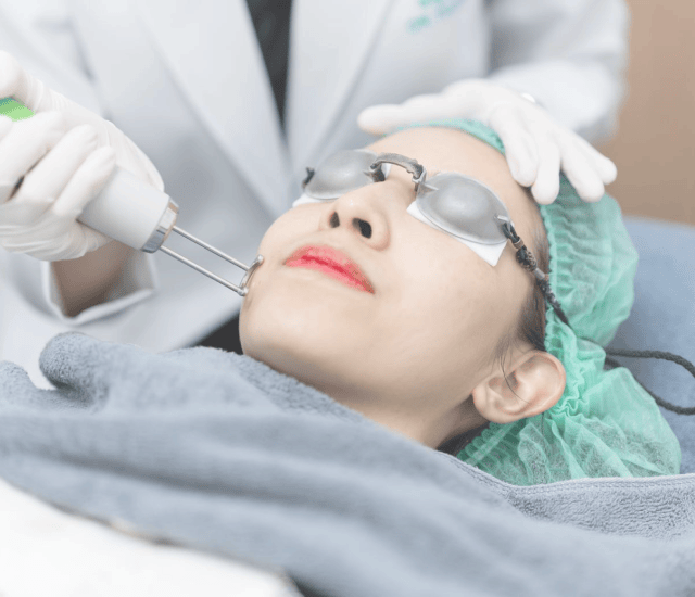 Doctor treating a patient's face with a laser handpiece during the Pigmentation Programme